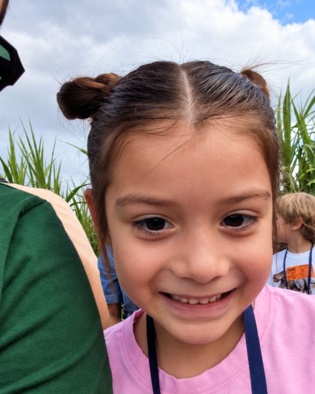 A smiling child with hair in two buns, wearing pink at the SCA field trip.